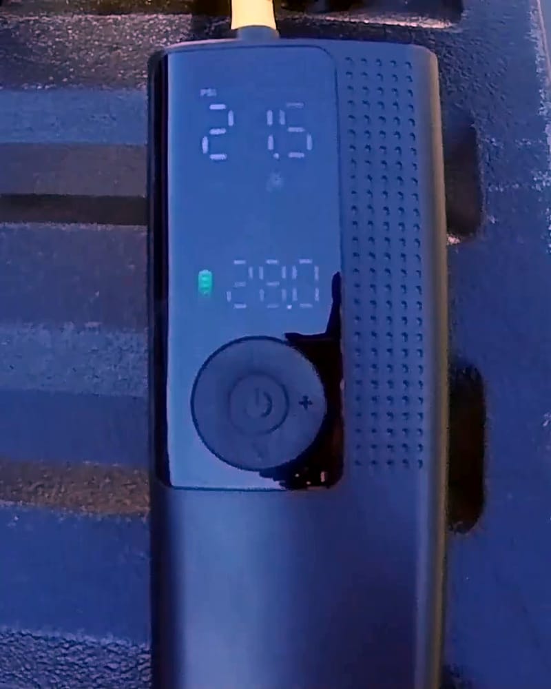 Black handheld tire inflator with its digital pressure display lit