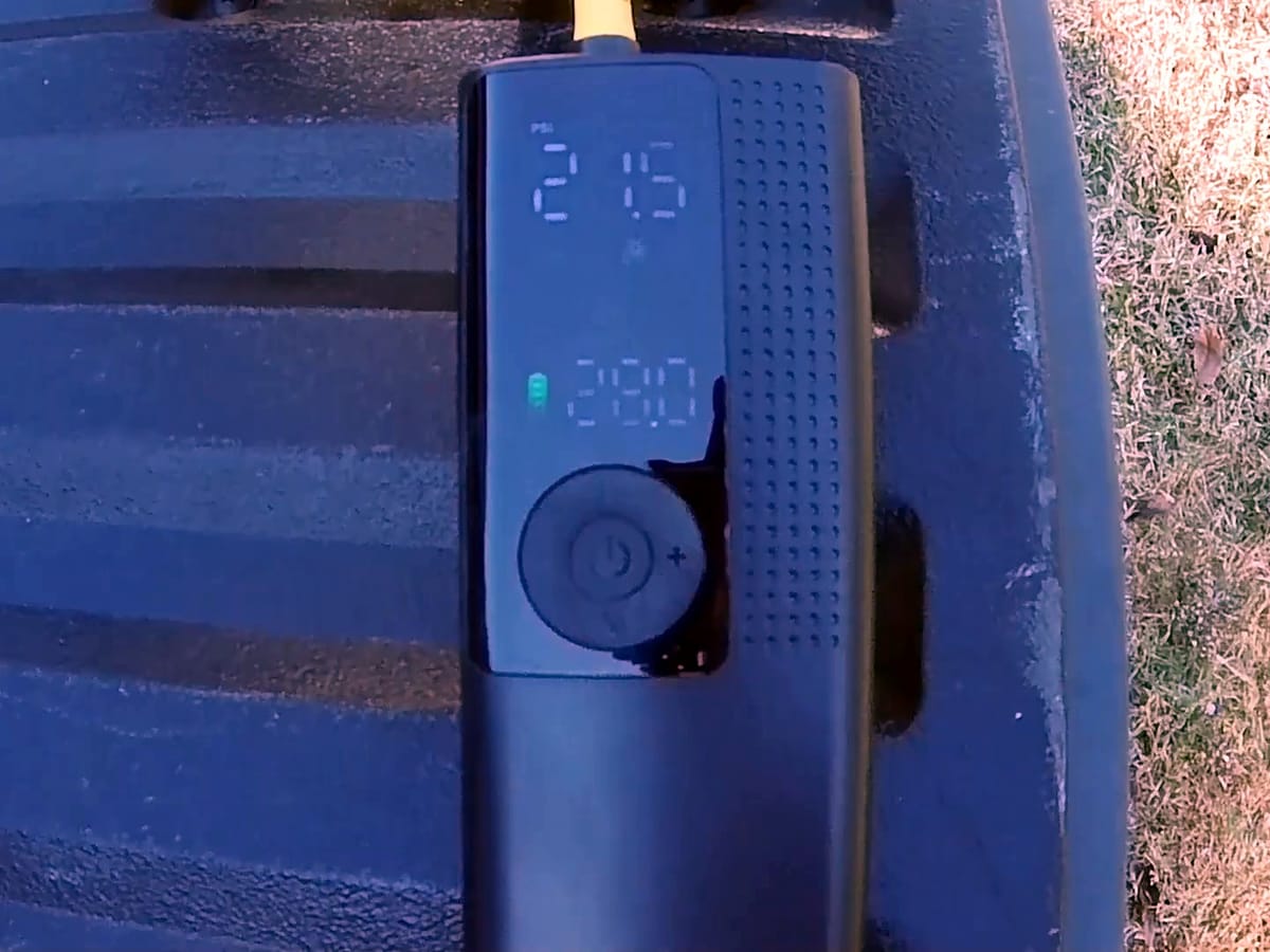 Black handheld tire inflator with its digital pressure display lit