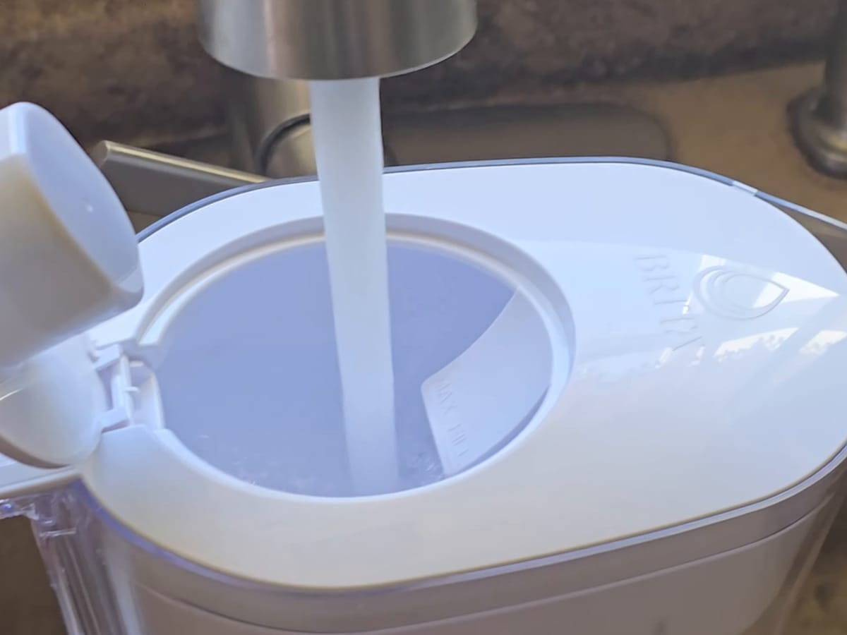 White water filter pitcher being filled from a kitchen tap